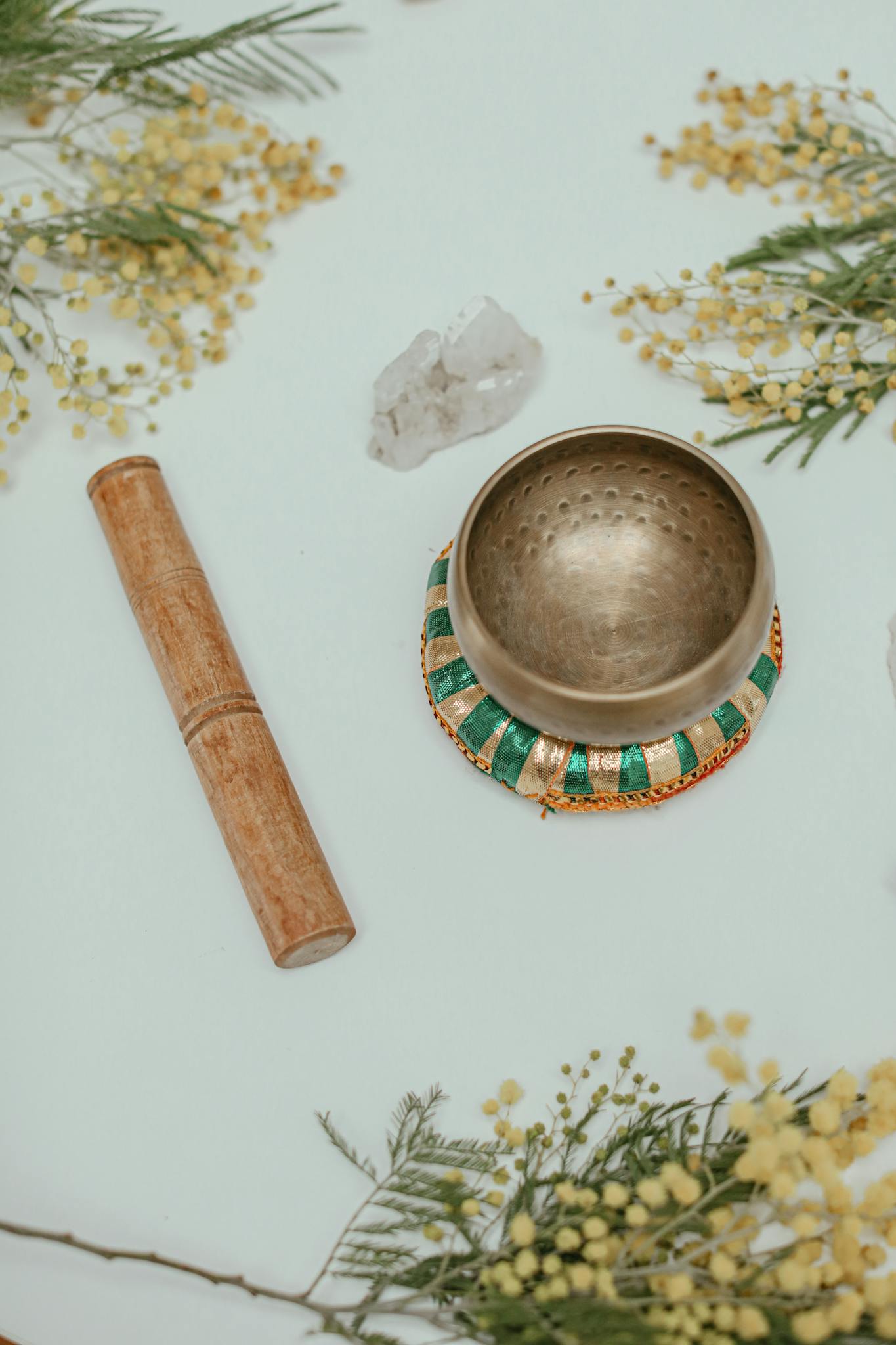 Tibetan singing bowl with crystals and yellow flowers on a serene background for relaxation and meditation.