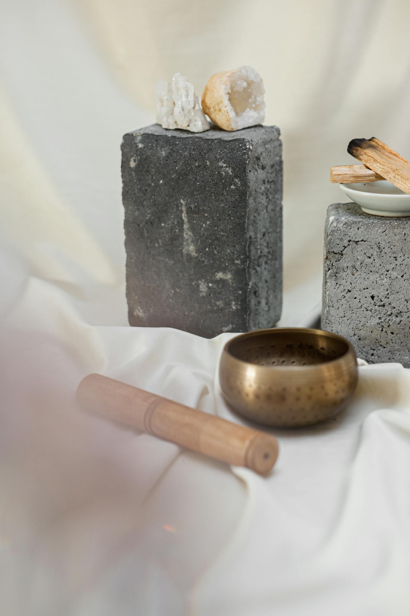 Tranquil setup featuring a Tibetan singing bowl, crystals, and incense for meditation and relaxation.